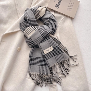 Close-up of classic grey plaid scarf with fringes and elegant label on wool coat