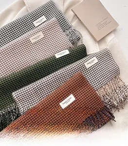 Dettaglio ravvicinato delle morbide nappe e delle etichette sulle sciarpe pied de poule