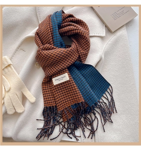 Dettaglio sciarpa pied de poule con frange e guanti in maglia su cappotto di lana