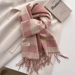 Detail of checkered scarf fringe and elegant textile label on white wool coat