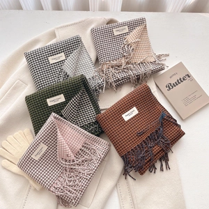 Dettagli di sciarpe pied de poule multicolore con frange su cappotto di lana beige