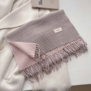 Dettaglio elegante sciarpa pied-de-poule con frange bicolore su sfondo cappotto minimalista