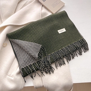 Dettaglio della sciarpa pied de poule verde scuro con frange su cappotto bianco