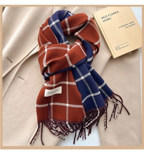 Detail of plaid scarf with tassels, rust red and navy blue pattern on wool coat