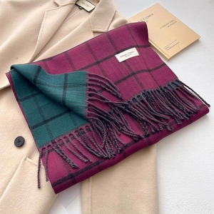 Detail of burgundy and green plaid scarf with long tassels on beige wool coat