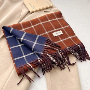 Plaid tassel scarf in caramel and navy blue on a beige coat with vintage prop book