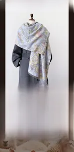 Detail of light blue winter scarf with floral jacquard pattern and soft fringe edges