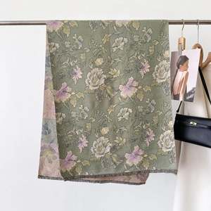 Detail of green jacquard scarf featuring pink floral patterns and fringe edge