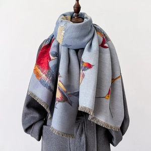 Elegant light blue long scarf with flying bird pattern and fringe on gray coat