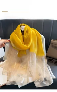Detail of yellow silk scarf featuring pearl and rhinestone clover patterns on gradient fabric
