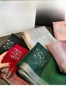 Detail of beaded clover pattern with sequins on elegant shimmering scarves in various colors