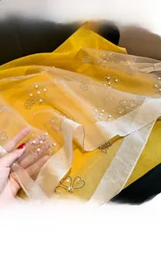 Detail of clover rhinestones and pearls on a gradient yellow faux silk shawl scarf