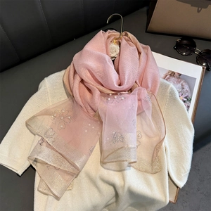 Detail of light pink scarf with pearl beads and clover sequins on soft knit fabric