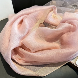 Detail of pink sheer scarf with gold shimmering edges and elegant silk-like texture