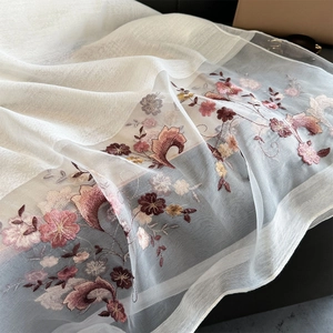 Detailed close-up of intricate floral embroidery on sheer lightweight white silk scarf