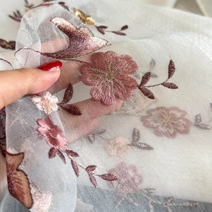 Close-up of translucent white scarf featuring intricate floral embroidery and texture