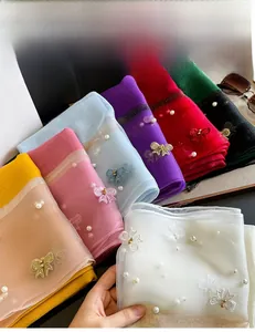 Détail de foulards en soie brodés avec des perles et des nœuds en paillettes