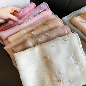 Détail d'une écharpe en soie brodée avec perles blanches et motifs de papillons