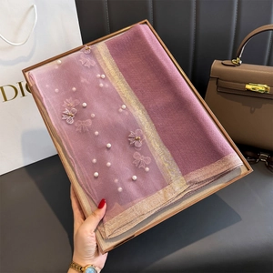 Détail de la broderie avec perles blanches et nœud 3D sur texture de foulard violet