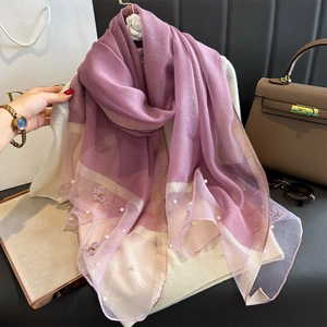 Détail d'une écharpe en soie dégradé violet avec broderie 3D et perles élégantes