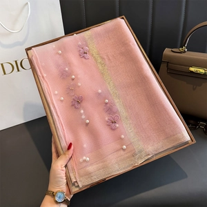 Détail d'une écharpe en soie rose avec broderies florales 3D et accents de perles blanches