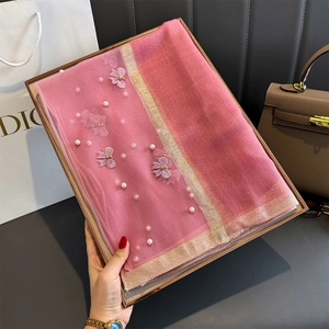 Détail d'un foulard en soie rose avec broderie florale et perles dans un coffret cadeau