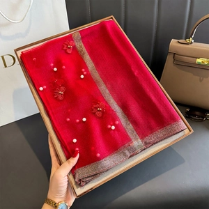 Détail d'une écharpe en soie rouge avec broderie perlée dans un coffret cadeau