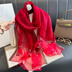Détail de l'écharpe en soie rouge avec broderie florale et finitions en perles élégantes