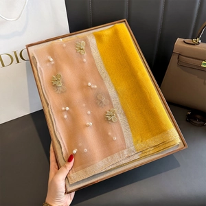 Détail d'une écharpe en soie avec broderie papillon dorée et perles sur satin jaune