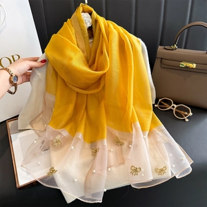Détail d'une écharpe en soie avec broderie nœud doré et ornements de perles blanches