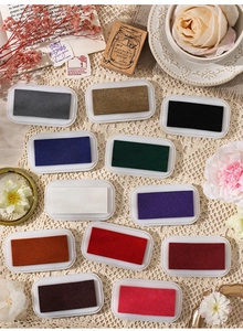 Flat lay of 12 multi-colored oil-based ink pads for journaling on vintage lace cloth