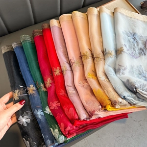 Close-up of multi-color silk scarves featuring floral embroidery and metallic edges