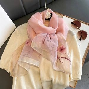 Light pink silk scarf with red flower embroidery and gold metallic edges shown on a sweater