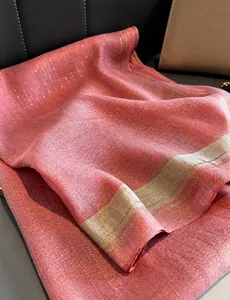 Detalle de bufanda de seda rosa con hilo dorado brillante y rayas beige decorativas
