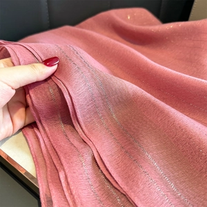 Detalle macro del chal rosa loto con tejido fino de hilos de seda dorados y brillantes