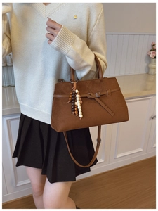 Detail of vintage brown suede tote bag featuring a decorative beaded charm and long strap
