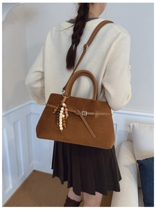 Detail of brown faux suede tote bag featuring beaded fringe and adjustable leather straps