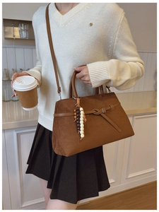 Detail of dark brown faux suede tote with wooden bead tassel and long shoulder strap