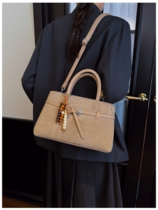 Detail of khaki suede tote bag with wooden bead pendant and detachable shoulder strap