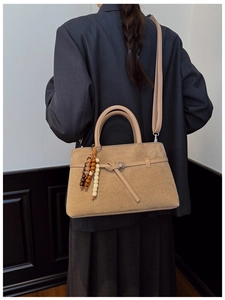 Detail of vintage matte leather tote bag with wooden bead charm and shoulder strap