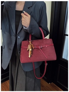 Detail of burgundy vintage suede tote with decorative wood bead tassel for women