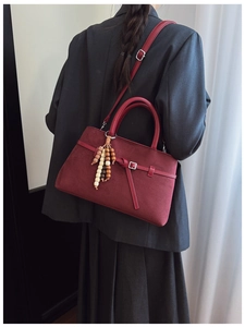 Detail of burgundy frosted suede tote bag featuring retro wooden bead pendant and silver hardware