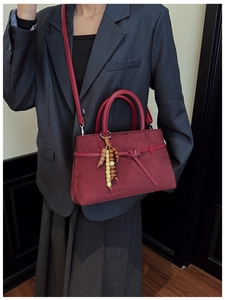 Detail of burgundy faux suede tote bag with metallic buckle and ethnic wood bead charm