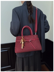 Detail view of burgundy frosted leather tote featuring a bead tassel and shoulder strap