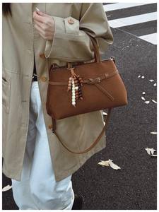 Detail of vintage brown suede tote with decorative buckle and beaded tassel charm
