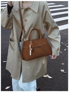 Close-up of brown matte leather tote bag with retro wooden bead tassel and strap details