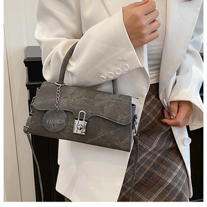 Detail of grey textured crossbody bag with silver padlock and fashion charm on model