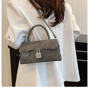 Close-up of grey textured suede crossbody bag with metal lock and fashion charm detail