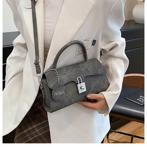 Close-up of retro dark gray textured crossbody bag with silver buckle and fashion tag