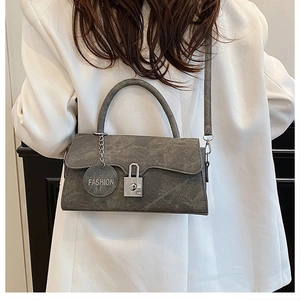 Detail of vintage charcoal grey textured crossbody bag with silver lock and fashion tag